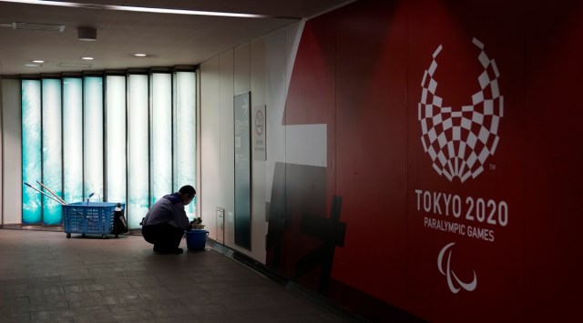 A worker cleans around a subway station next to a sign promoting the Tokyo 2020 Paralympic Games during the 2020 Summer Olympics (Source: AP)