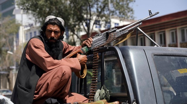 A Taliban fighter sits on the back of a vehicle with a machine gun in front of the main gate leading to the Afghan presidential palace, in Kabul, Afghanistan. (AP Photo/Rahmat Gul)