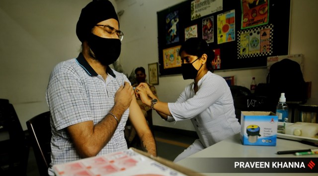 A beneficiary takes a shot of Covid-19 vaccine at a vaccination centre in New Delhi. (Express photo by Praveen Khanna)