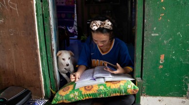 Annie Sabino, 16, a grade 9 student, completes her school work next to her dog, while tending to her family's sidewalk eatery beside their home, as schools remain closed during the coronavirus disease (Covid-19) outbreak, in Manila, Philippines, January 6, 2021 | Reuters/File Photo