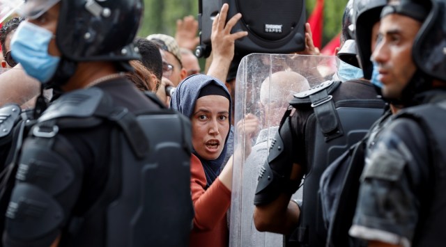 Police officers stand guard as a demonstrator tries to force her way during a protest against Tunisian President Kais Saied's seizure of governing powers. (Reuters)