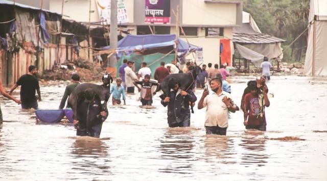 
The Konkan area faced two cyclones – Nisarga and Tauktae -- in the last two years. Residents of Valdhuni in Kalyan wade through a flooded street. (Express Photo: Deepak Joshi)