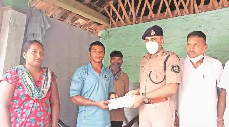 Mahesh Jadav, elder brother of Ravi Jadav, receives a cheque  of Rs 3 lakh from Navsari SP rushikesh Upadhyay. (Express)