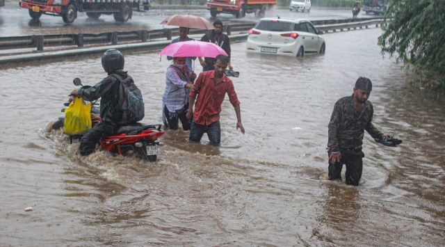 Commuters wade through a waterlogged road during heavy rains, in Gurgaon. (PTI/File)