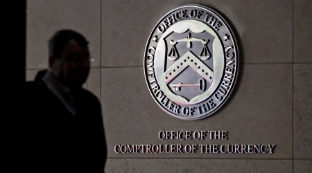 A pedestrian passes the seal of the Office of the Comptroller of the Currency (OCC) displayed outside the organization's headquarters in Washington, D.C., U.S., on Wednesday, March 20, 2019. (Bloomberg)