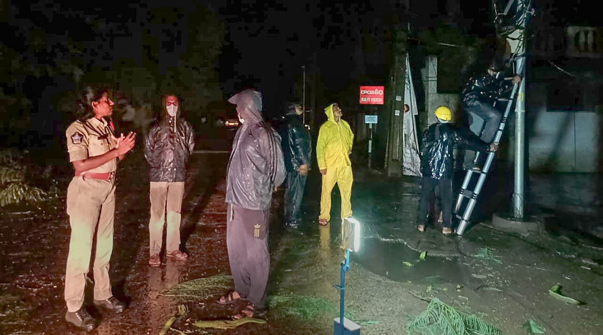 Police personnel and locals at a site after a tree fell down due to heavy winds induced by Cyclone Gulab, in Srikakulam (PTI)