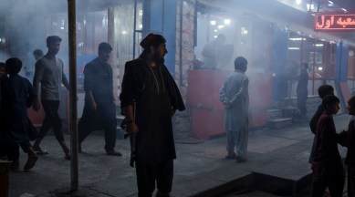 An armed Taliban fighter stands in the corner of a busy street at night in Kabul, Afghanistan. (AP)