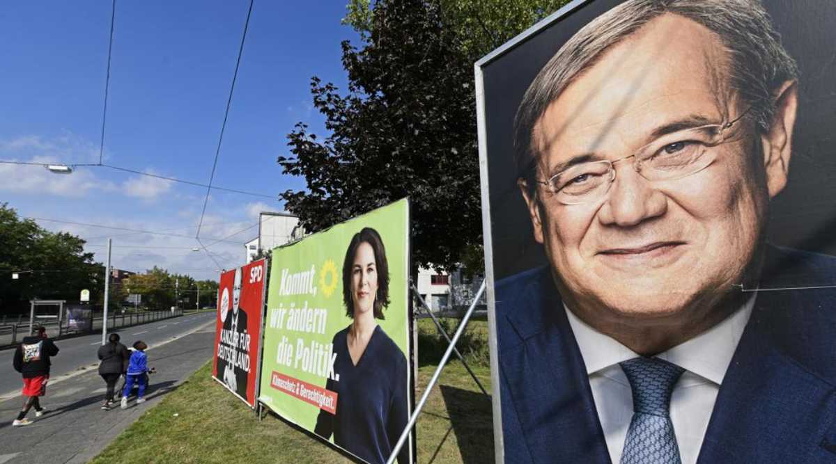 People walk past election posters of the three chancellor candidates, from right, Armin Laschet, Christian Democratic Union (CDU), Annalena Baerbock, German Green party (Die Gruenen) and Olaf Scholz, Social Democratic Party (SPD), at a street in Gelsenkirchen, Germany, Thursday, Sept. 23, 2021 three days before the General election on Sunday, Sept. 26, 2021. (AP Photo)