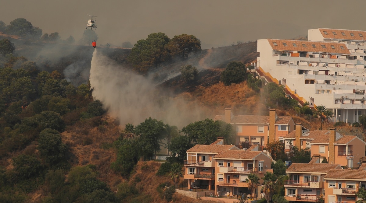 A helicopter makes a water drop over a wildfire burning near buildings on Sierra Bermeja mountain in Estepona, Spain, Sept. 9, 2021. (Reuters)
