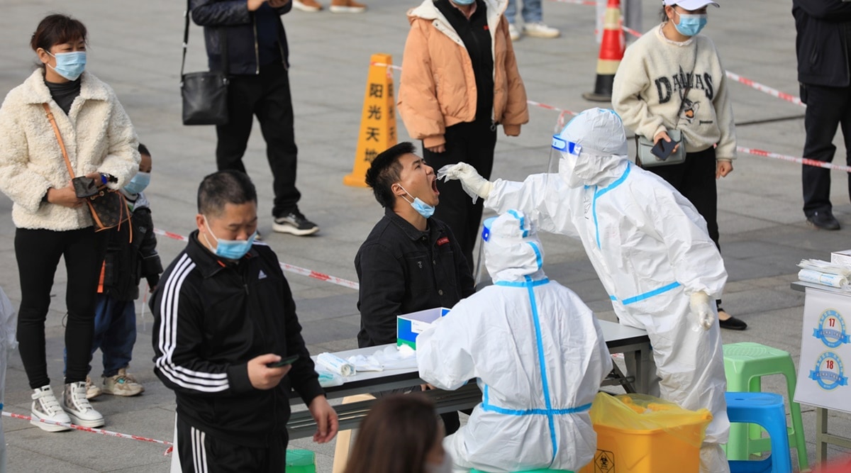 A medical worker in protective suit collects a swab from a man during a mass nucleic acid testing in Huichuan district following new cases of Covid-19 in Zunyi, Guizhou province, China. (Reuters)