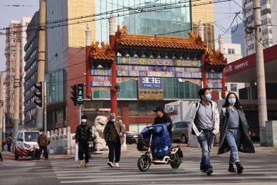 People wearing face masks cross a street in Beijing, following outbreaks of the coronavirus disease in China, October 25, 2021. (Reuters)