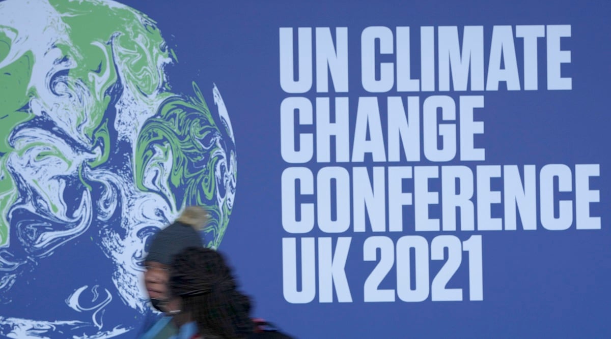 Attendees walk past a banner at the venue where COP climate conference will be held in Glasgow, Scotland. (AP)