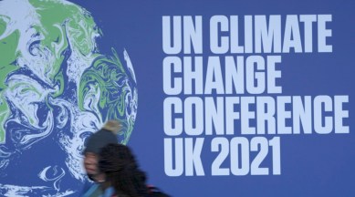 Attendees walk past a banner at the venue where COP climate conference will be held in Glasgow, Scotland. (AP)