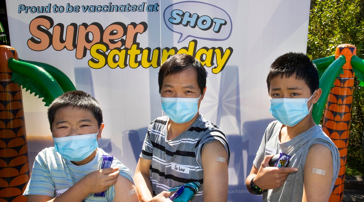 Johnson, left, Bailou, center, and Benson Su of Auckland show their patches after receiving their vaccination in Auckland, New Zealand. (Brett Phibbs/NZME via AP)