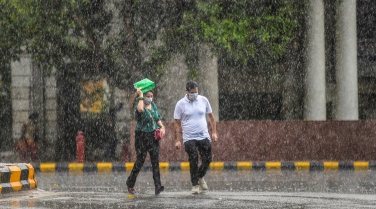 Pedestrians walk in heavy rain at Connaught Place in New Delhi, Sunday, Oct. 17, 2021. (PTI Photo)