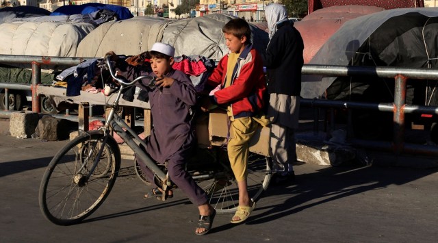 Boys ride a bicycle at Pole Bagh Omomy market in Kabul, Afghanistan on Oct. 15, 2021. (Reuters)