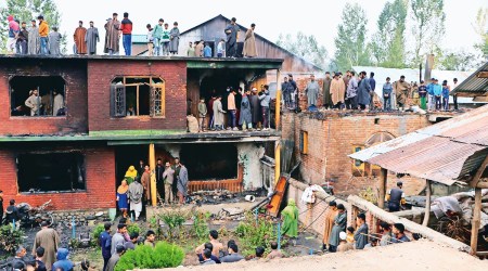 People inspect a partially damaged house at the site of the encounter in Shopian’s Tulran village. (Photo: Shuaib Masoodi)