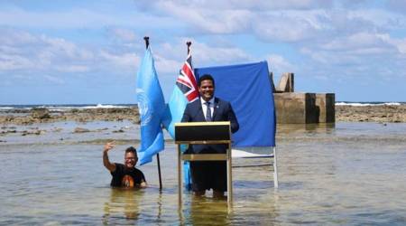 Tuvalu's Minister for Justice, Communication & Foreign Affairs Simon Kofe gives a COP26 statement while standing in the ocean in Funafuti