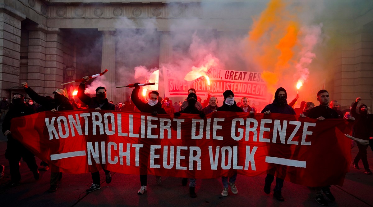 Demonstrators shout slogans and light flares during a demonstration against measures to battle the coronavirus pandemic in Vienna, Austria, Saturday, Nov. 20, 2021. Banner reads: ' Controls the border. Not your people'. (AP)
