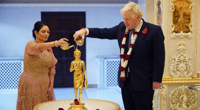 Britain's Prime Minister Boris Johnson, right and Home Secretary Priti Patel pour water over a gilded brass image of Shri Nilkanth Varni (Bhagwan Swaminarayan) in a ceremony as they attend Diwali celebrations during their visit to the Hindu temple, BAPS Shri Swaminarayan Mandir, in Neasden, London. (AP)