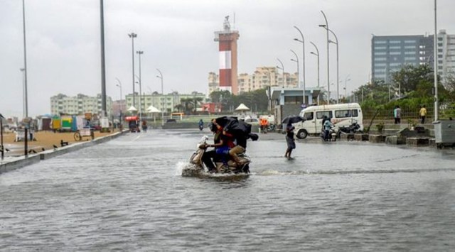 People riding a scooter wade through a waterlogged road after heavy rain near Marina Beach, in Chennai, Friday, Nov. 26, 2021 (PTI)