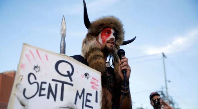 Jacob Chansley, holding a sign referencing QAnon, speaks as supporters of U.S. President Donald Trump gather to protest about the early results of the 2020 presidential election, in front of the Maricopa County Tabulation and Election Center (MCTEC), in Phoenix, Arizona November 5, 2020. (File Photo: Reuters)