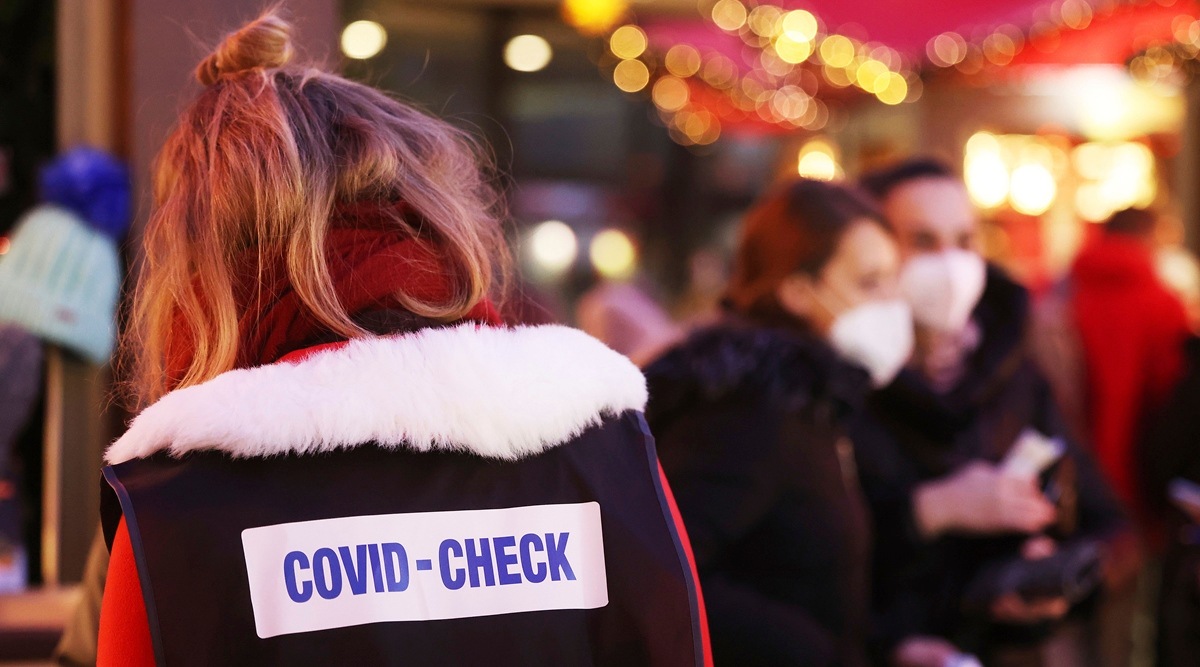 An inspector appointed by the exhibitors, wearing a sign on her back reading "Covid Check", walks through Christmas market on Roncalliplatz near the cathedral to check visitors in Cologne, Germany. (AP)