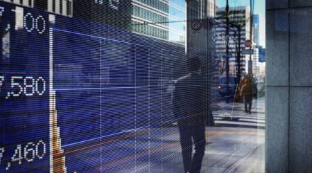 A pedestrian is reflected in an electronic stock board outside a securities firm in Tokyo. (Bloomberg)