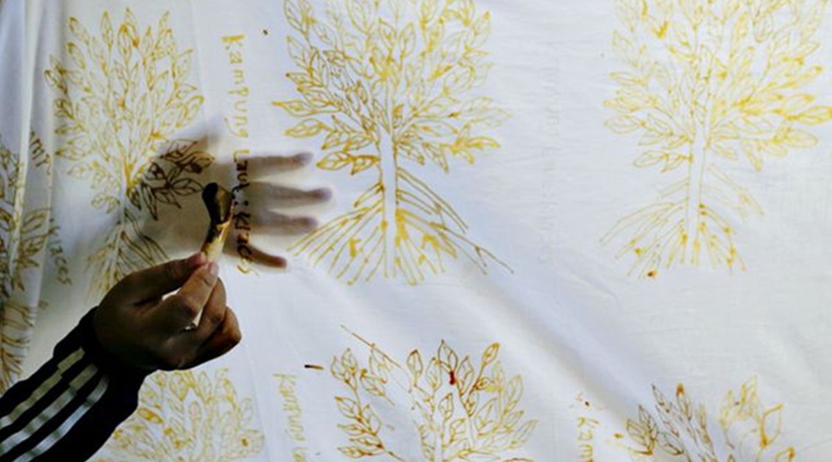 A mangrove batik worker draws a batik pattern on a white cotton cloth in Klaces village, Cilacap, Central Java province, Indonesia, November 4, 2021. (Reuters)