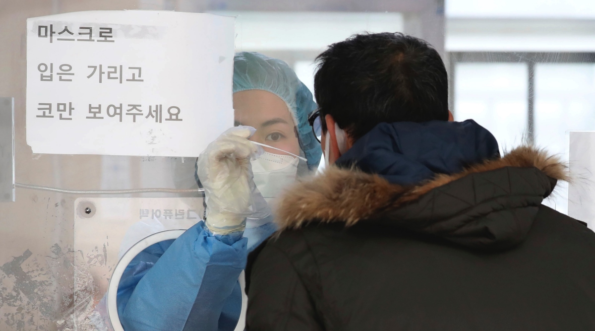 A medical worker wearing protective gear in a booth, takes sample from a man at a temporary screening clinic for the coronavirus in Seoul, South Korea, Saturday, Dec. 4, 2021. (Park Mi-so/Newsis via AP)