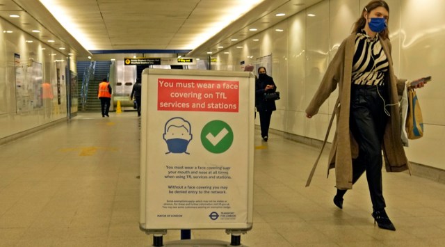 A commuter walks past an information poster telling passengers that it is compulsory to wear a face mask on public transport to curb the spread of Covid-19, in London. (AP)