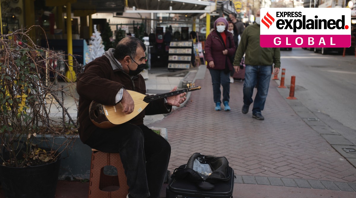 A man plays a saz or baglama, a traditional instrument of Turkish folk music, to make some money in street, in Ankara, Turkey, Sunday, Dec. 12, 2021. (AP Photo/Burhan Ozblici)