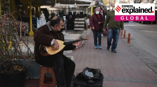 A man plays a saz or baglama, a traditional instrument of Turkish folk music, to make some money in street, in Ankara, Turkey, Sunday, Dec. 12, 2021. (AP Photo/Burhan Ozblici)