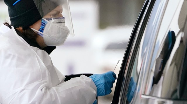 COVID-19 testing specialist Susana Blasco reaches forward with a swab to test a driver at a drive-up coronavirus testing location Tuesday, Dec. 21, 2021, in Bellingham, Wash. (AP)