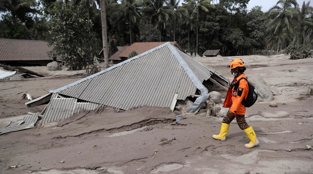A rescuer walks past a house buried in the ash following the eruption of Mount Semeru in Lumajang district. (AP)
