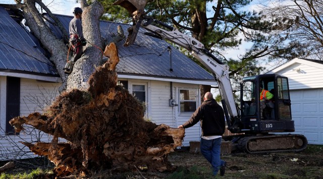 Workers remove a fallen tree off of a house after a devastating outbreak of tornadoes ripped through several US states, in Mayfield, Kentucky. (Reuters)