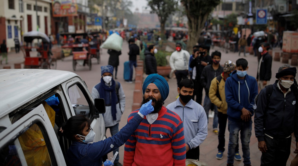 A healthcare worker collects a coronavirus disease (COVID-19) test swab sample from a man as others wait, amidst the spread of the disease, at a market area, in the old quarters of Delhi, India, January 7, 2022. (Reuters)