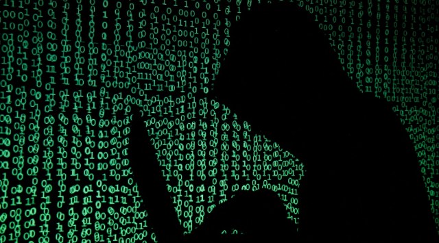 Hooded man holds laptop computer as cyber code is projected on him in this illustration picture.