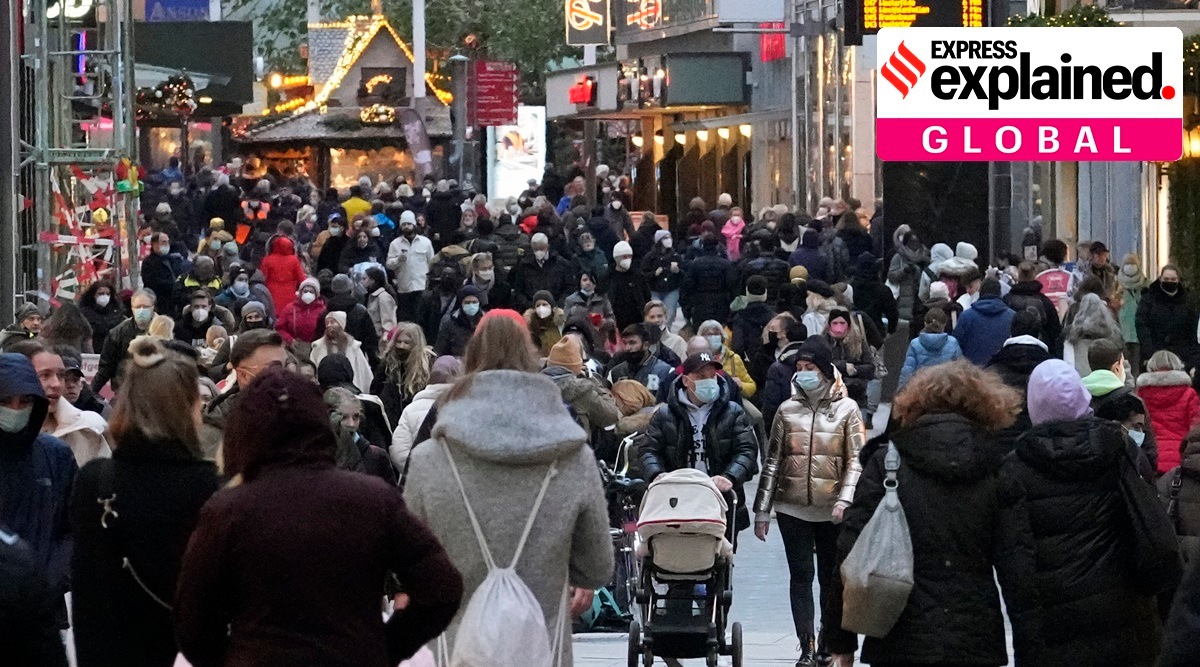 People wear mandatory face masks walk along a street in Dortmund, Germany, Dec. 1, 2021. (AP Photo/Martin Meissner, File)

