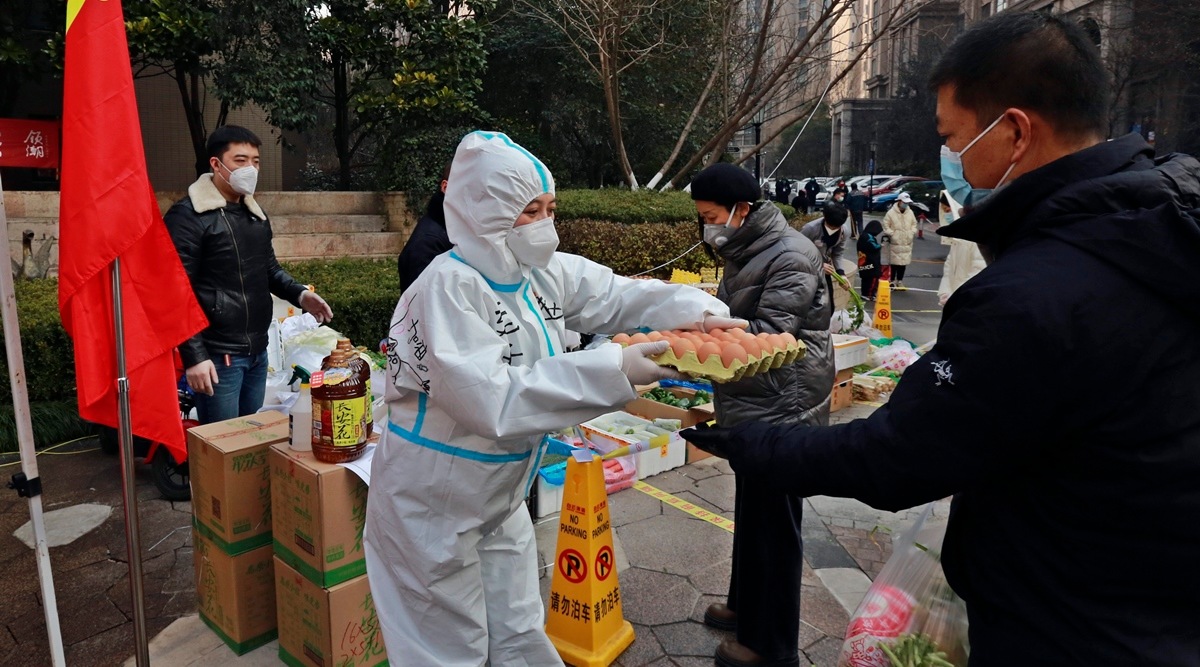 A community volunteer hands over eggs to a buyer at a temporary food store to provide supplies to residents outside a residential block in Xi'an city in northwest China's Shaanxi province Monday, January 03, 2022. (AP)
