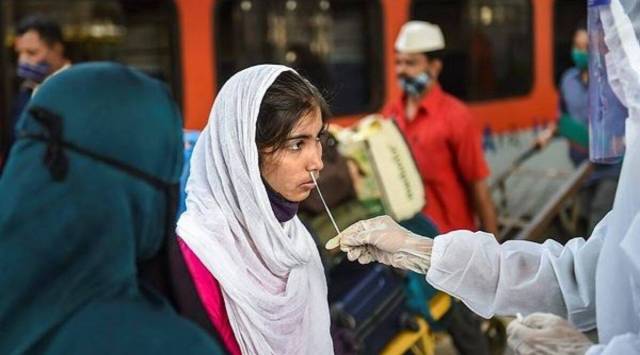 A health worker collects a sample of a traveler to test for COVID-19, at Dadar railway station in Mumbai. (PTI)