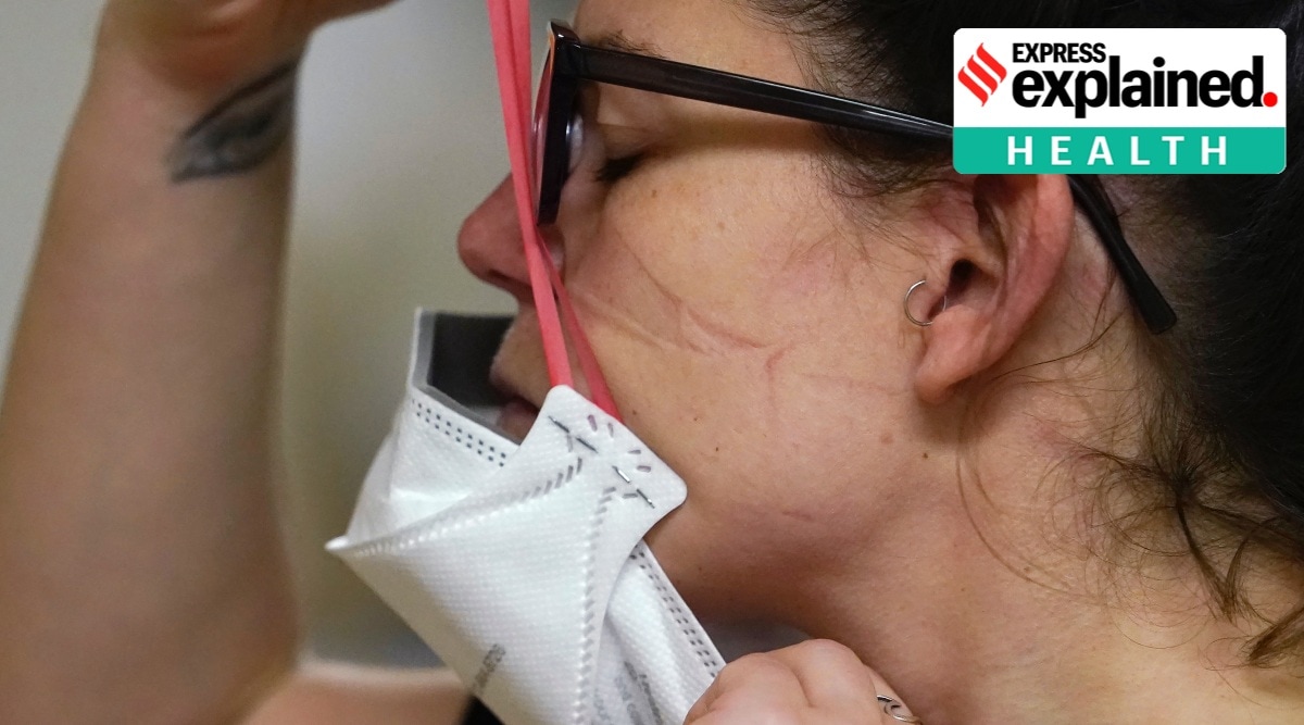 A resident of Seattle pulls on a N95 mask. (AP Photo/Elaine Thompson, File)