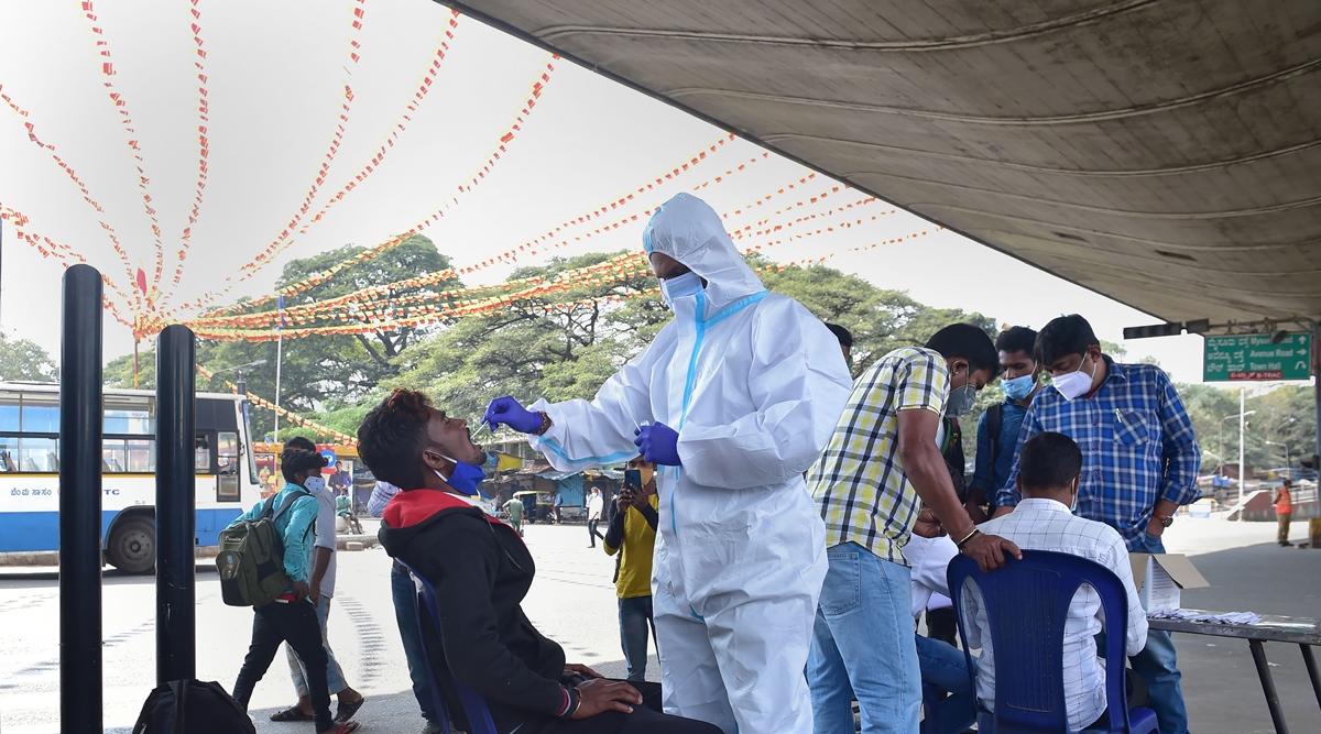 A health worker collects swab sample of a passenger for Covid-19 test at K R Market in Bengaluru. (PTI)