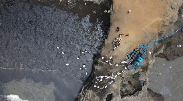 Workers continue in a clean-up campaign after an oil spill, on Cavero Beach in the Ventanilla district of Callao, Peru, Saturday, Jan. 22, 2022. The oil spill on the Peruvian coast was caused by the waves from an eruption of an undersea volcano in the South Pacific nation of Tonga. (AP Photo/Martin Mejia)