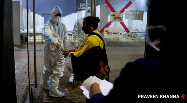 Medical staff sanitize a Covid positive patient before admission inside the Covid Care Centre, in New Delhi on Wednesday. (Express Photo by Praveen Khanna)