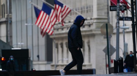 A pedestrian is framed by American flags flying outside the New York Stock exchange, Friday, Jan. 14, 2022, in the Financial District. (AP Photo/Mary Altaffer)



