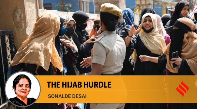 Muslim students wearing hijab interact with a policewoman as they gather to protest at a government school in Bengaluru, Karnataka, Thursday, Feb. 17, 2022. (AP Photo/Aijaz Rahi)