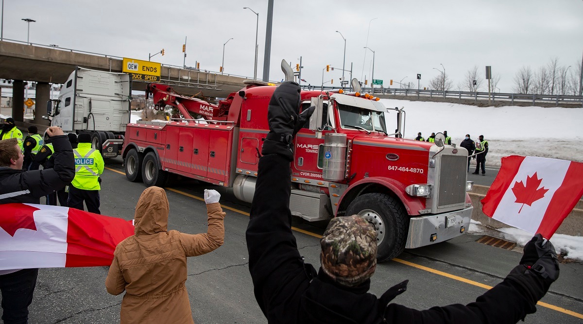 A truck passes Ontario Provincial Police officers and demonstrators in opposition to COVID-19 mandates on the Toronto-bound QEW highway after crossing the Peace Bridge in Fort Erie, Ontario. (AP)