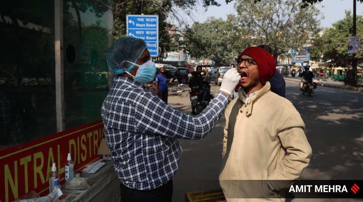 A health worker collects swab sample of a man in New Delhi. (Express Photo By Amit Mehra)