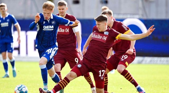 Karlsruhe's Tim Breithaupt, left, and Schalke's Florian Flick fight for the ball during the 2. Bundesliga match between Karlsruher SC and FC Schalke 04 in Karlsruhe, Germany, on Saturday, Feb. 26, 2022 . The Schalke team taped over the logo of main sponsor Gazprom on the jerseys due to the Russian war in Ukraine. (Uli Deck/dpa via AP)